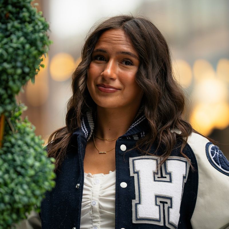 Close portrait of a senior in a letterman jacket with soft city bokeh